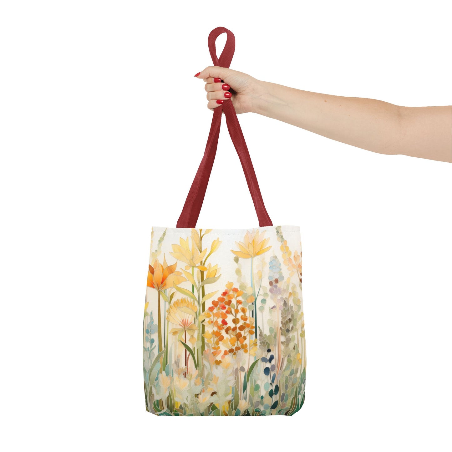 A hand with red nail polish holds the Stained Glass Fall Flowers Tote Bag, showcasing an original artist design in yellow, orange, and green shades. The bag, featuring vibrant red handles, is crafted from durable polyester materials.