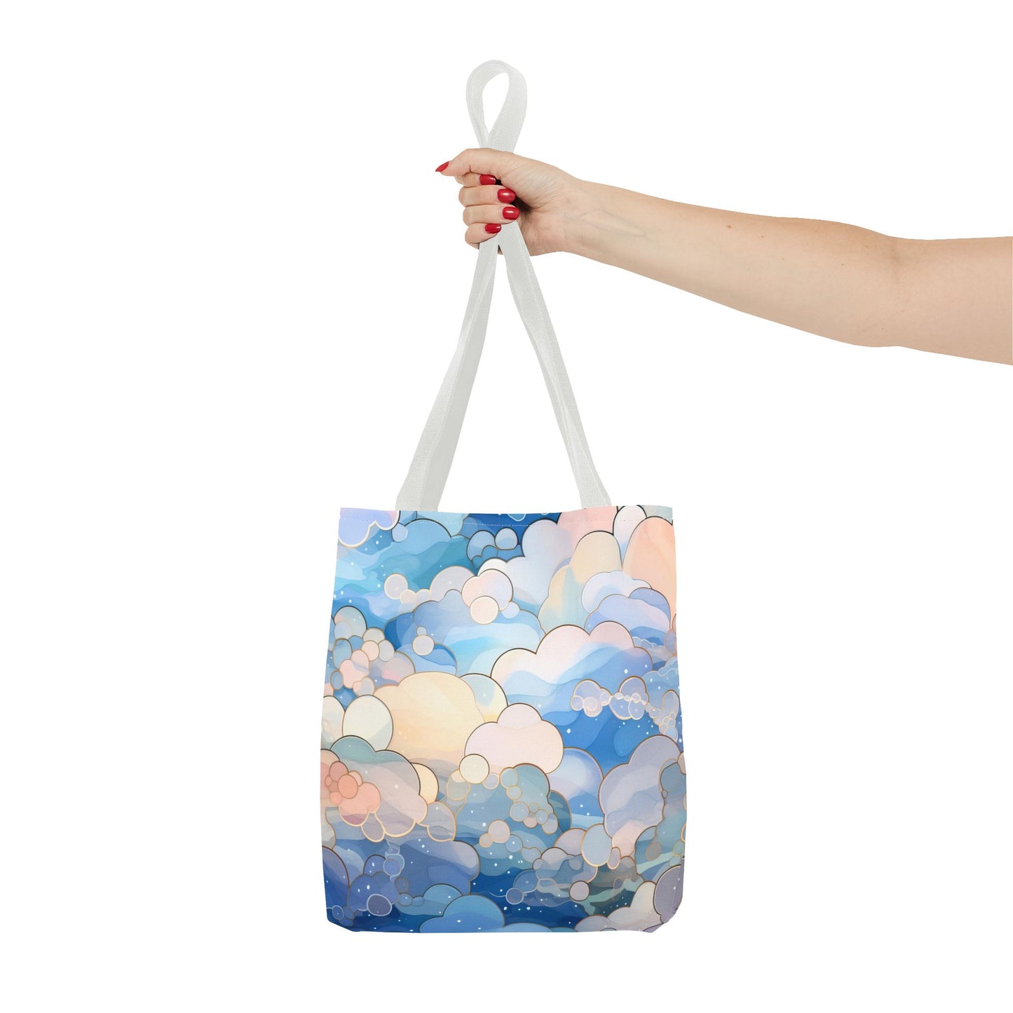 A hand with red nail polish holds the Stained Glass Clouds Tote Bag, featuring an abstract design in blue, peach, and white against a light backdrop. The durable polyester bag has white handles.