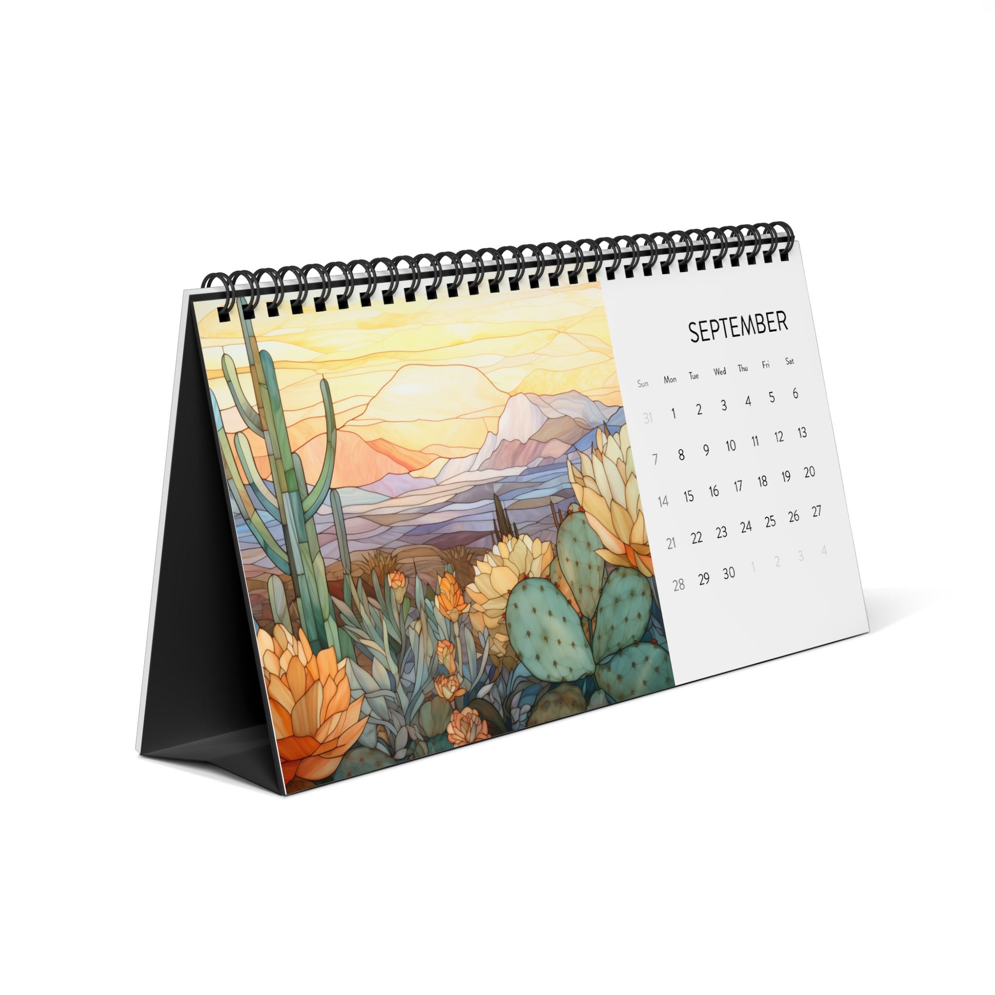 The 2025 Desk Calendar - Desert Landscapes, open to September, features high-quality paper stock and showcases stained glass illustrations of cacti and flowers set against a stunning desert landscape.