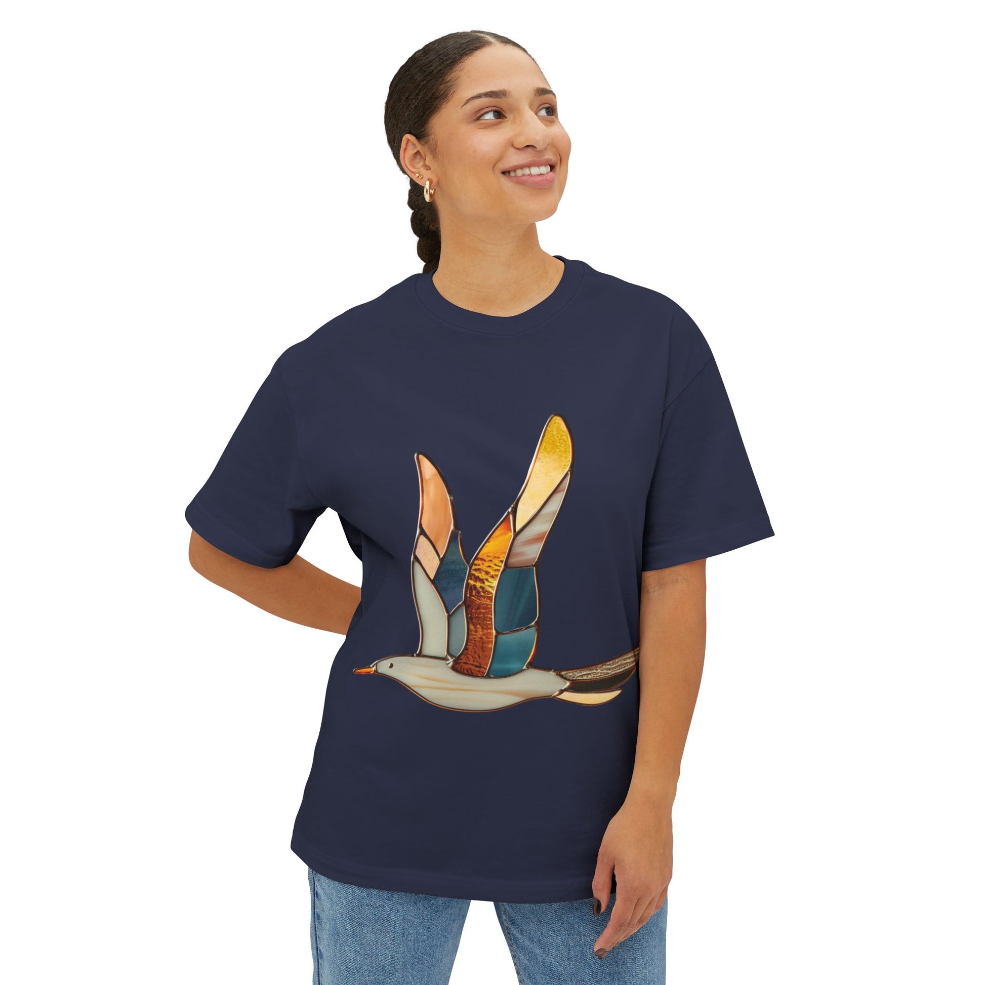 A person wearing a dark blue Stained Glass Seagull Oversized Tee Shirt stands against a plain white background, looking up and smiling.