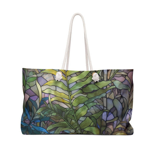 The Stained Glass Ferns Weekender Oversized Tote Bag boasts a colorful abstract design with green leaves and purple accents, inspired by stained glass. This boho-style bag features sturdy white handles, making it a perfect artful addition to any outing.