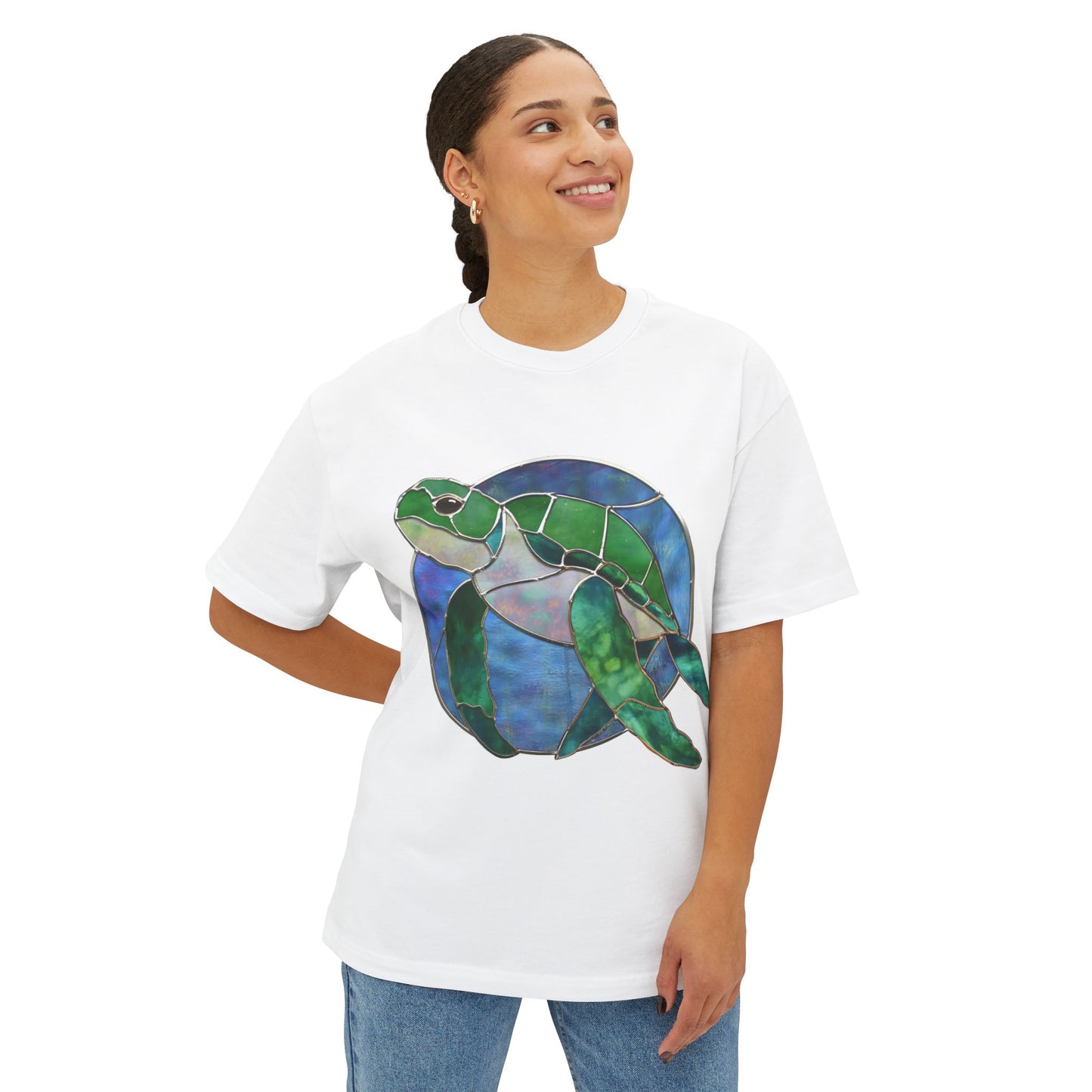 A person stands smiling, wearing a Bella+Canvas Stained Glass Turtle Oversized Tee Shirt featuring a colorful turtle design by Noelle Barnes.