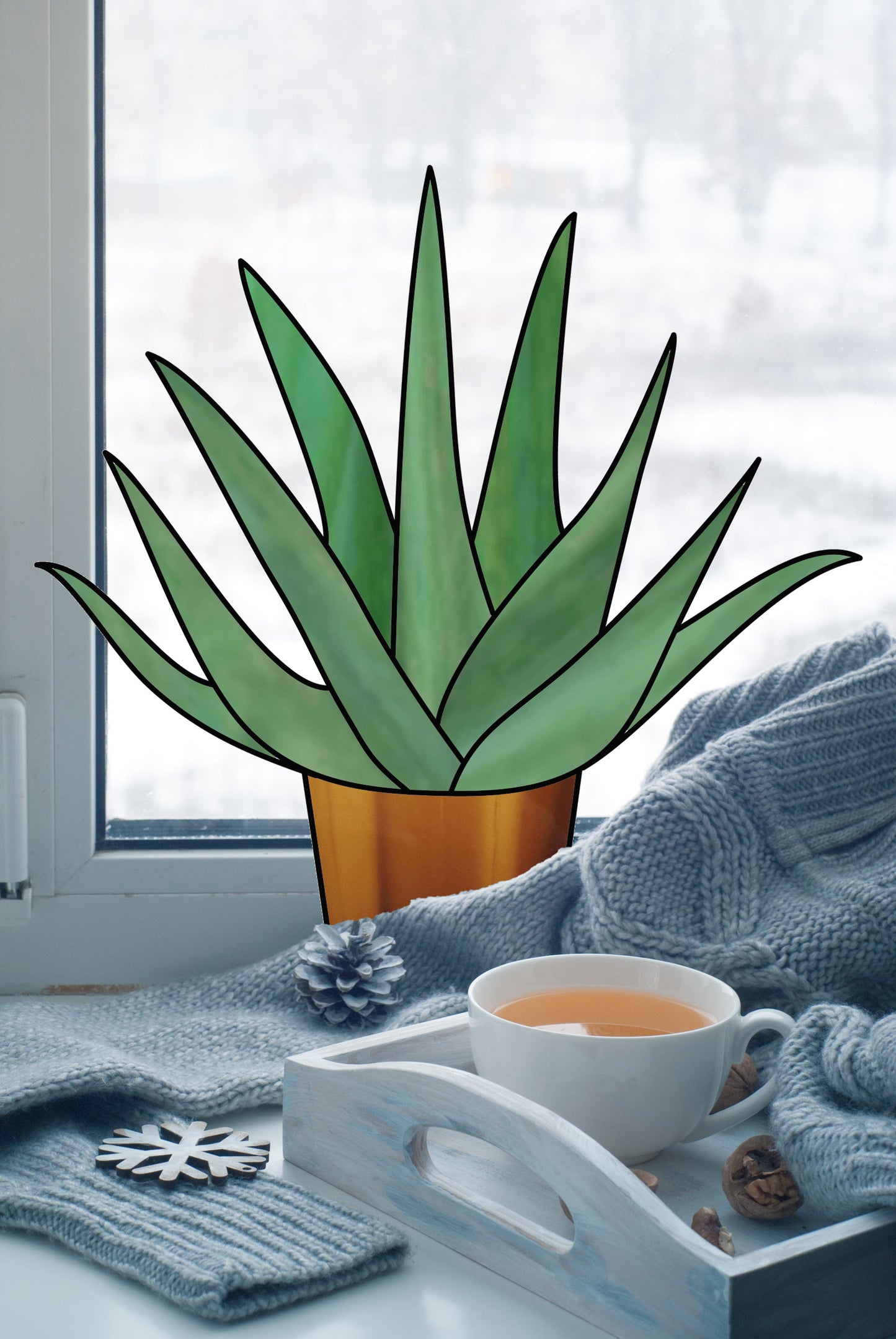 A Beginner Aloe Potted Plant with a stained glass pattern sits on the windowsill. A wooden tray nearby holds tea, walnuts, and a pine cone. A cozy blue knit blanket is draped around the scene as snowflakes dance outside.