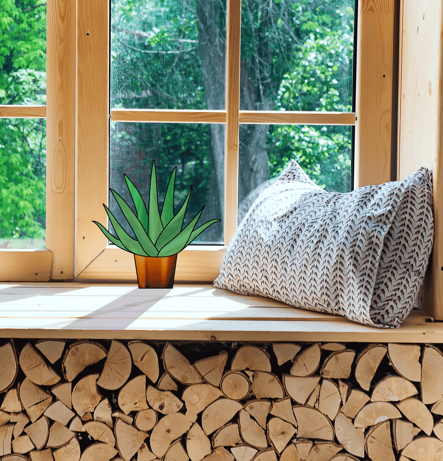 A window seat with patterned cushions overlooks lush greenery. Beside the cushion is a potted aloe plant in an amber vase, and neat stacks of firewood sit beneath it. Sunlight catches a stained glass pattern, creating a cozy atmosphere. Product: Beginner Aloe Potted Plant Stained Glass Pattern.