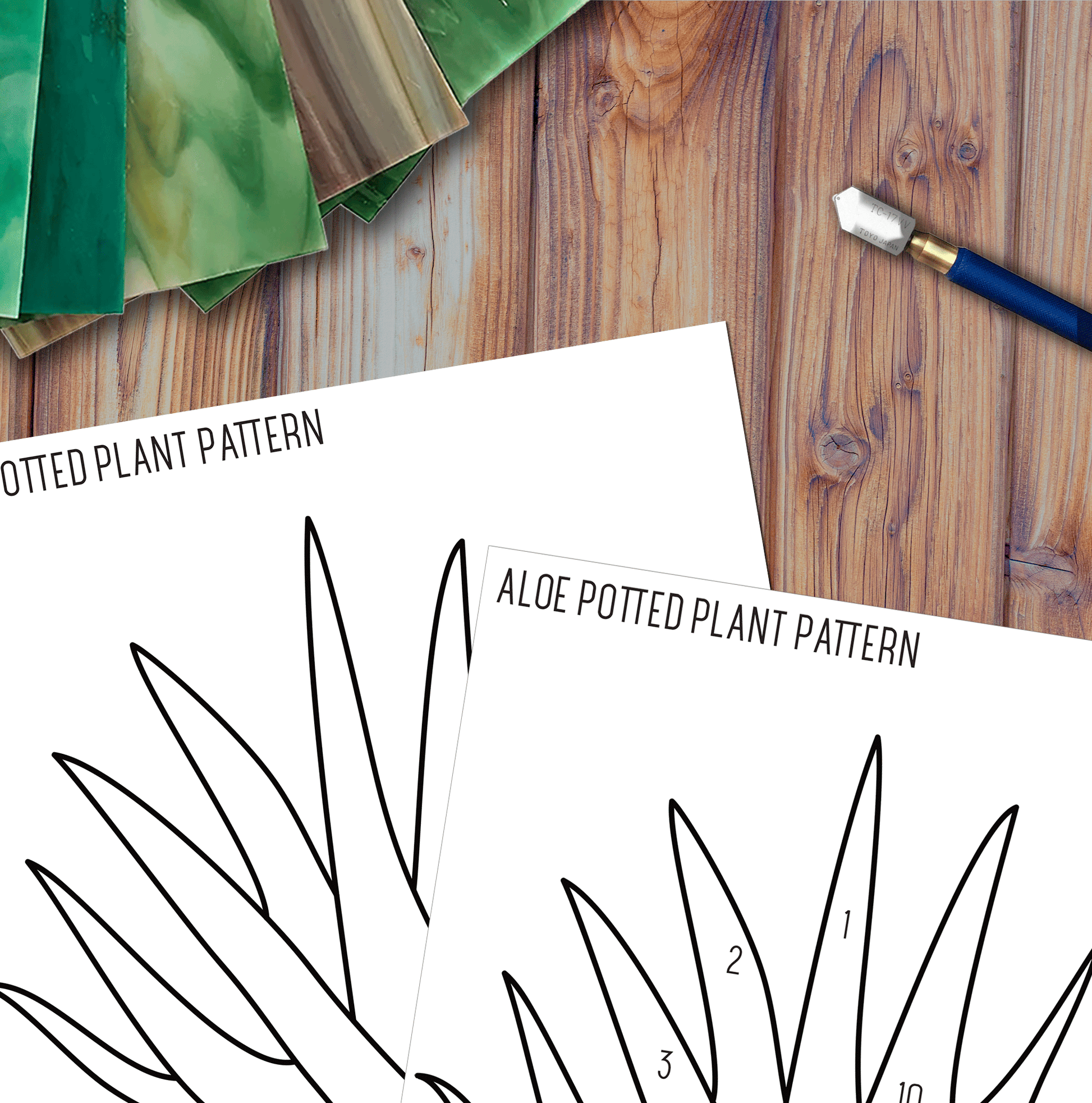 The Beginner Aloe Potted Plant Stained Glass Pattern sheets lie on a wooden surface, paired with a craft knife and green gradient paper sheets, creating a welcoming workspace for DIY projects.