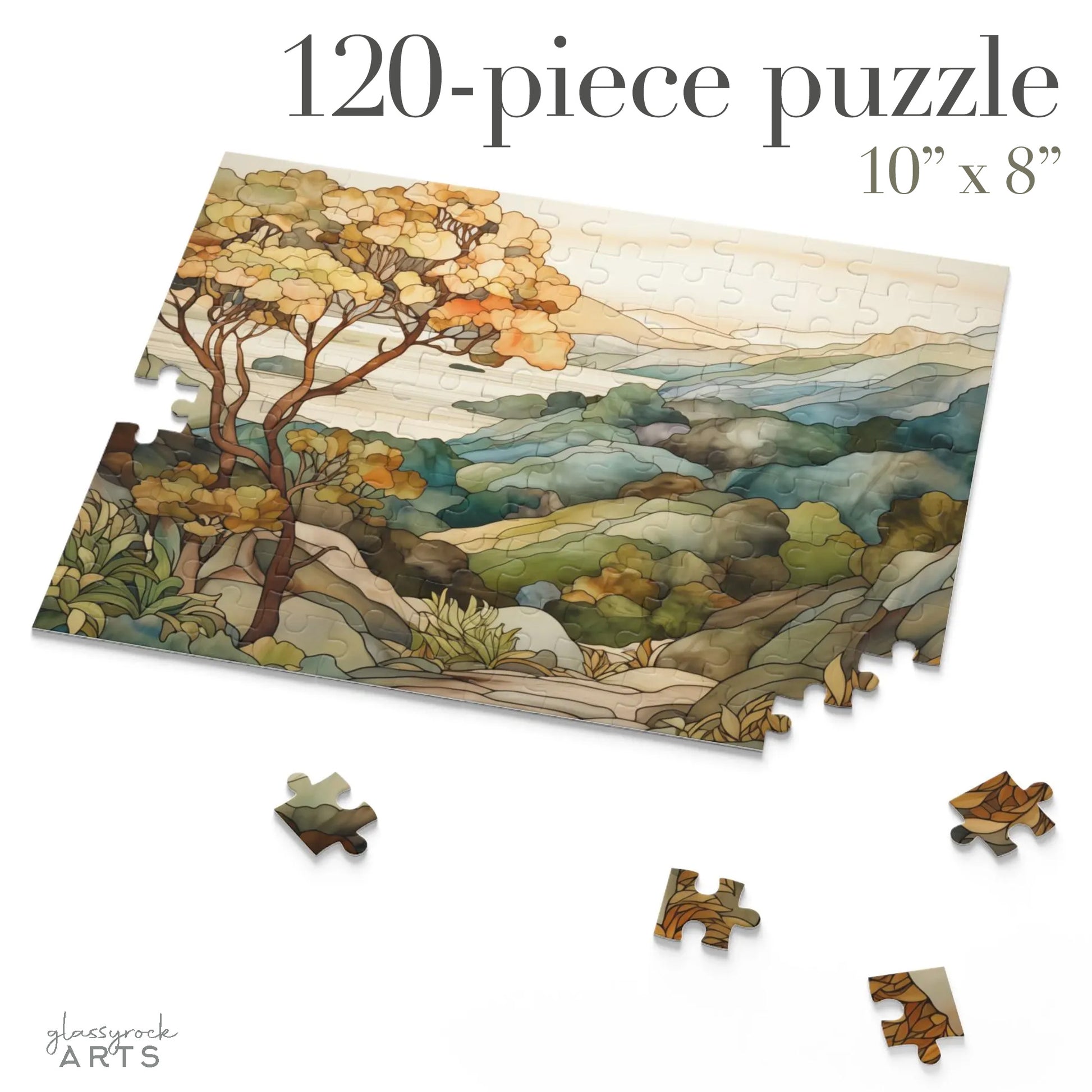 A jigsaw puzzle with a coastal scene of the Big Sur area of California, with a large tree on the left and mountains on the right and ocean in the distance. The illustration is in a stained glass style in muted colors.  120 pieces.