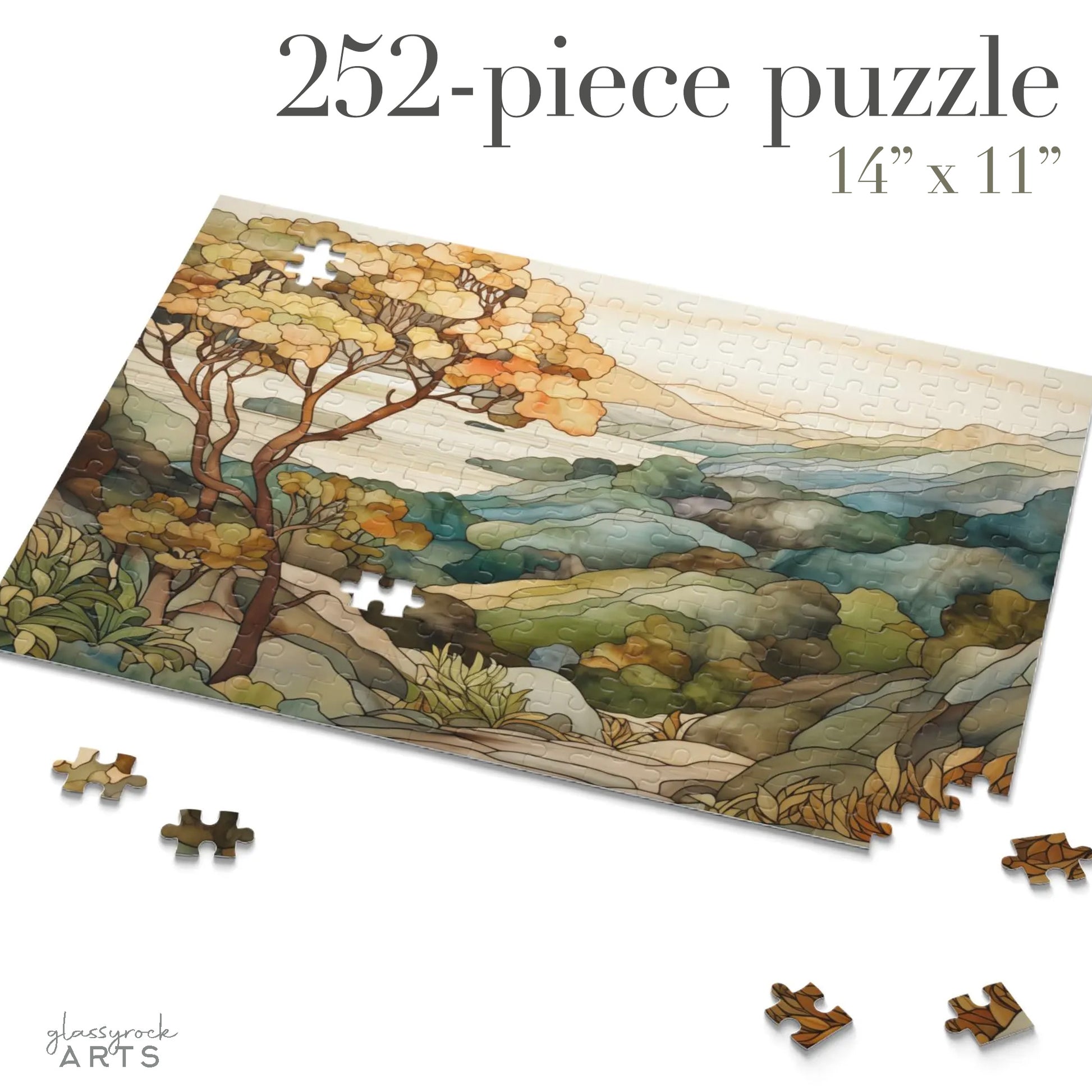 A jigsaw puzzle with a coastal scene of the Big Sur area of California, with a large tree on the left and mountains on the right and ocean in the distance. The illustration is in a stained glass style in muted colors. 252 pieces.