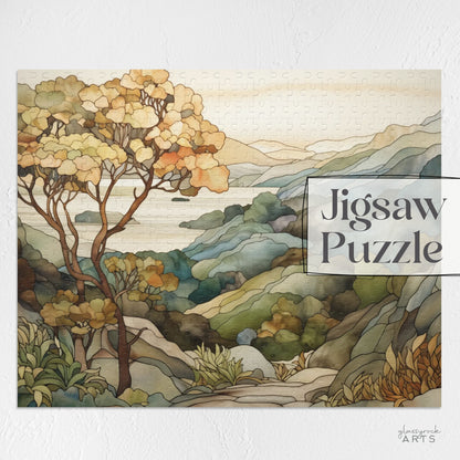 A jigsaw puzzle with a coastal scene of the Big Sur area of California, with a large tree on the left and mountains on the right and ocean in the distance. The illustration is in a stained glass style in muted colors. 