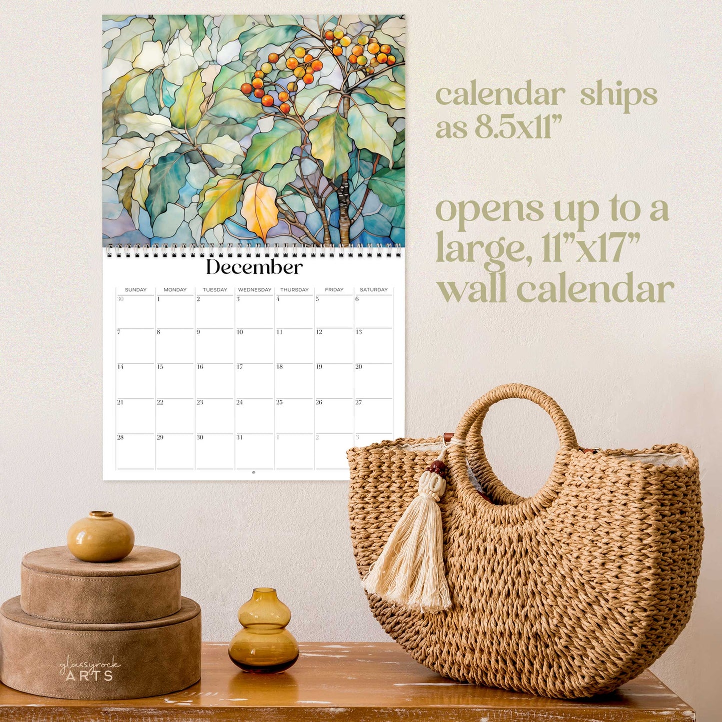 The birth flowers calendar, a 2025 monthly wall calendar with floral-themed original artwork, on a wall above a wood table with a wicker purse. The calendar is open to December, showing holly.