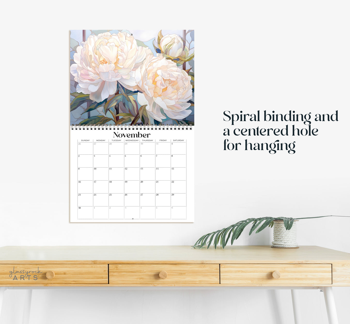 This calendar has a spiral binding and a centered hole for hanging.