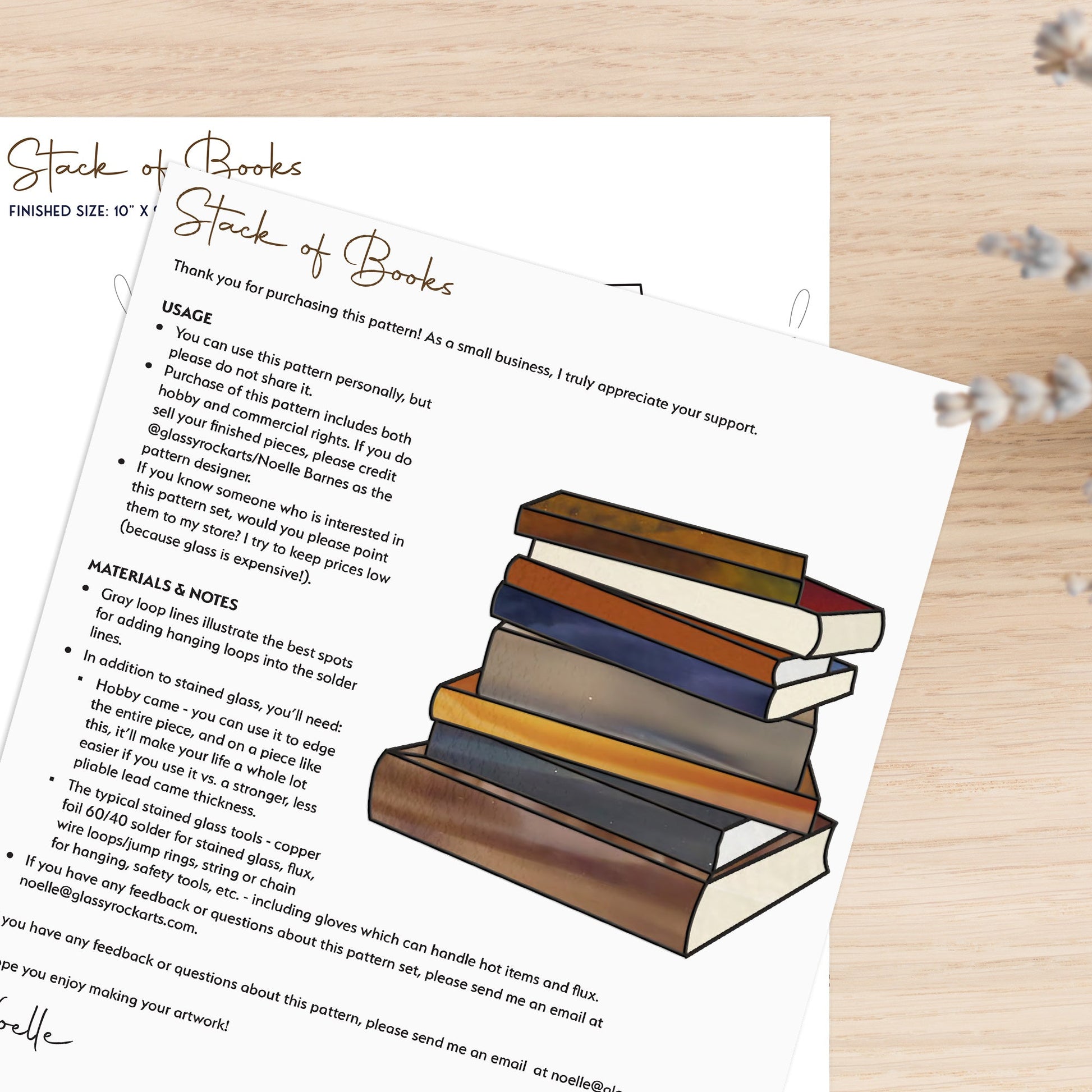 The Books Stained Glass Pattern showcases a stack of books with an overlay of usage instructions and material details, ideal as a gift for book lovers. Handwritten notes and decorative text appear on a light wooden surface with a small plant nearby.