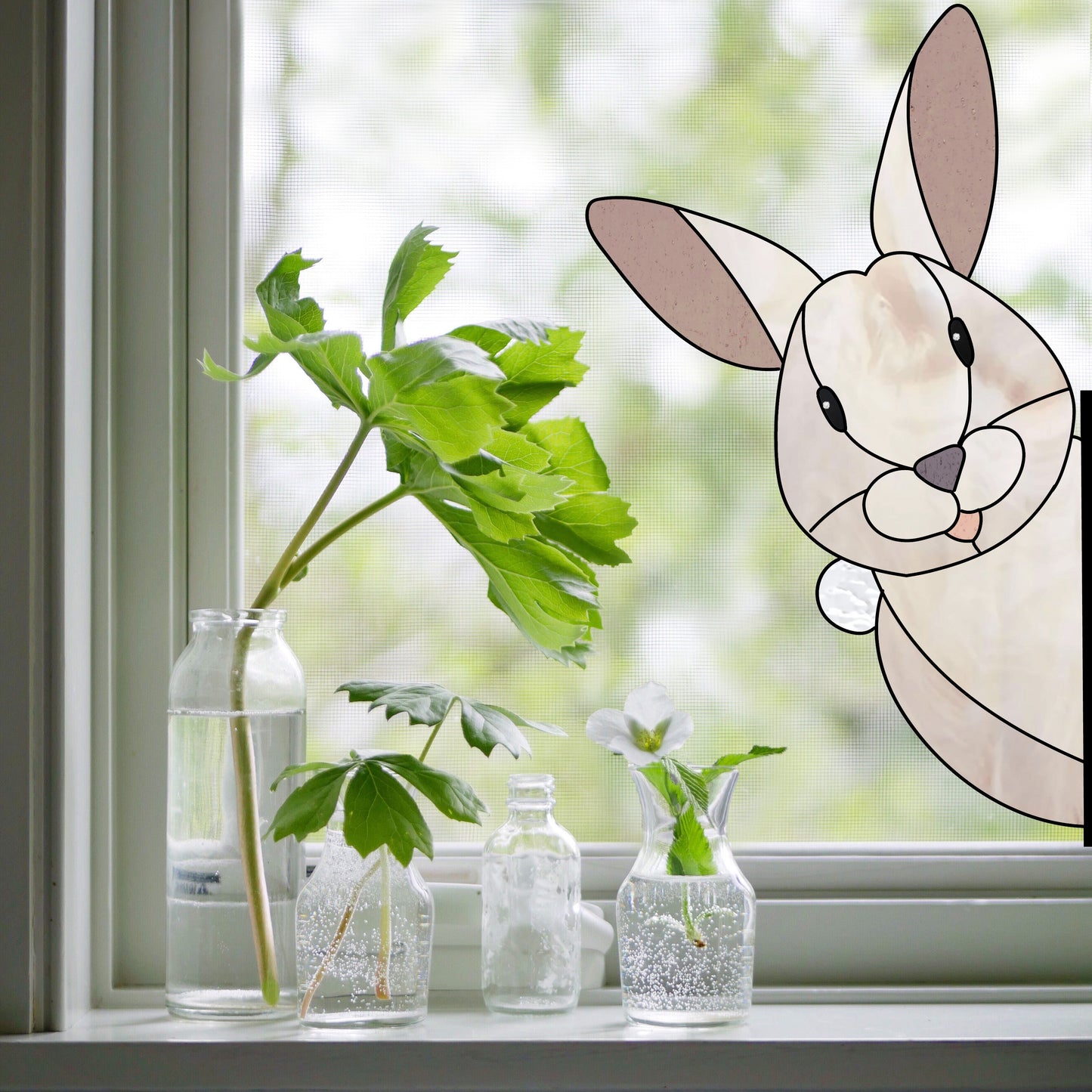 A cartoon bunny peers through a window with green plants in clear bottles, evoking the Rabbit Buddy Bunny Stained Glass Rabbit Pattern. The softly blurred greenery in the background adds a fresh, airy vibe.