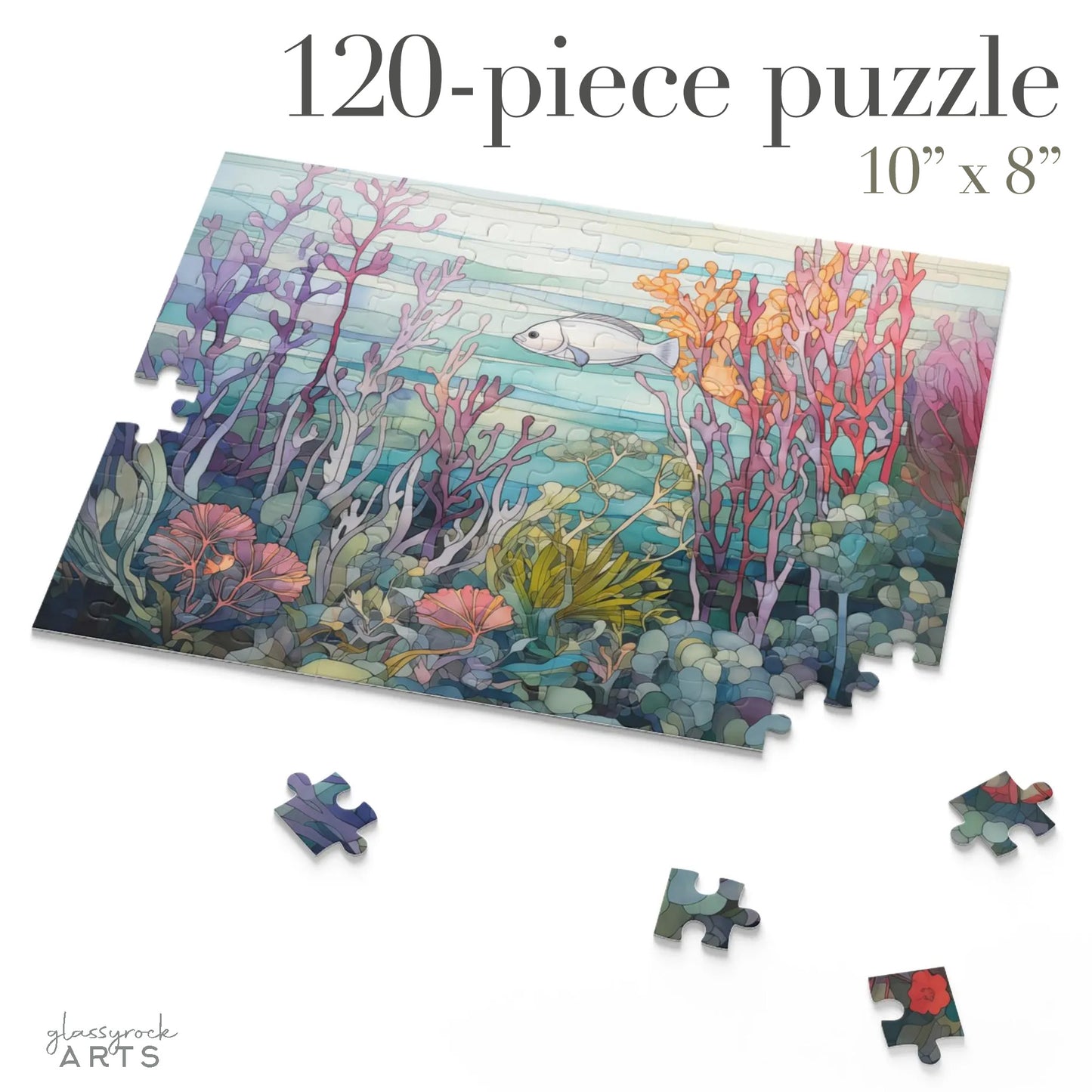 An image of a jigsaw puzzle featuring a stained glass illustration of a silver fish swimming amongst a purple, orange and pink coral reef. 120 pieces.