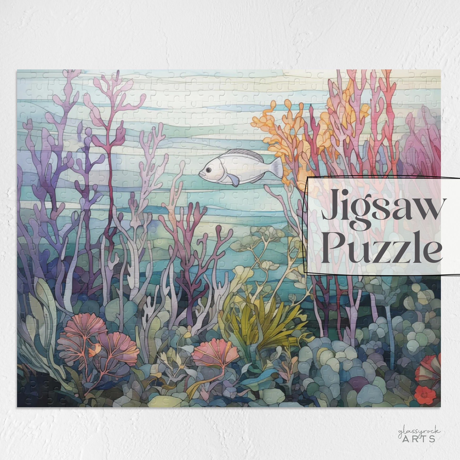 An image of a jigsaw puzzle featuring a stained glass illustration of a silver fish swimming amongst a purple, orange and pink coral reef. 