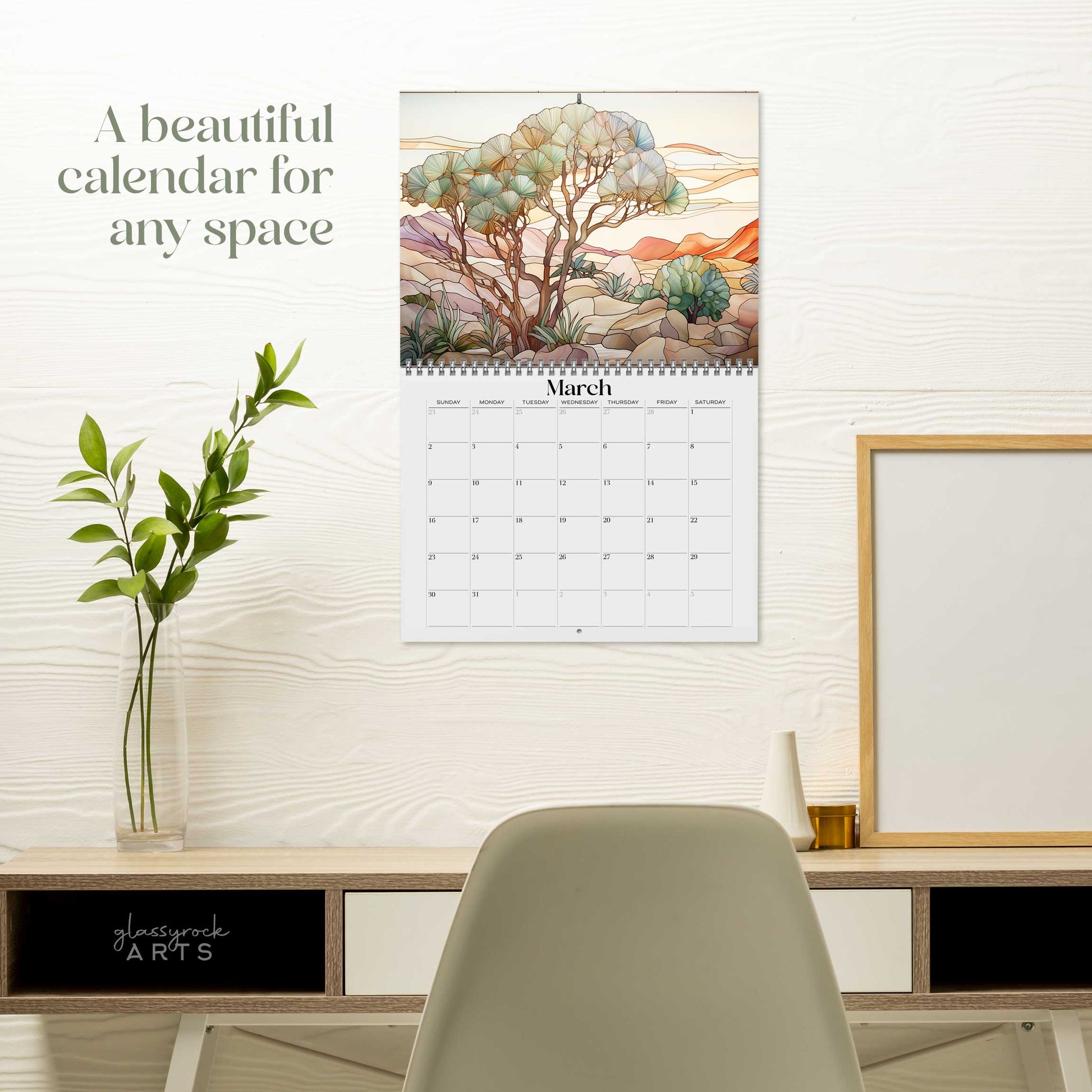 The 2025 Wall Calendar - Stained Glass Desert Landscapes, with spiral binding and a centered hole for hanging, features vivid desert illustrations. 