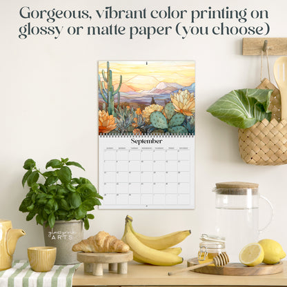 The 2025 Wall Calendar - Stained Glass Desert Landscapes, with spiral binding and a centered hole for hanging, features vivid desert illustrations. 