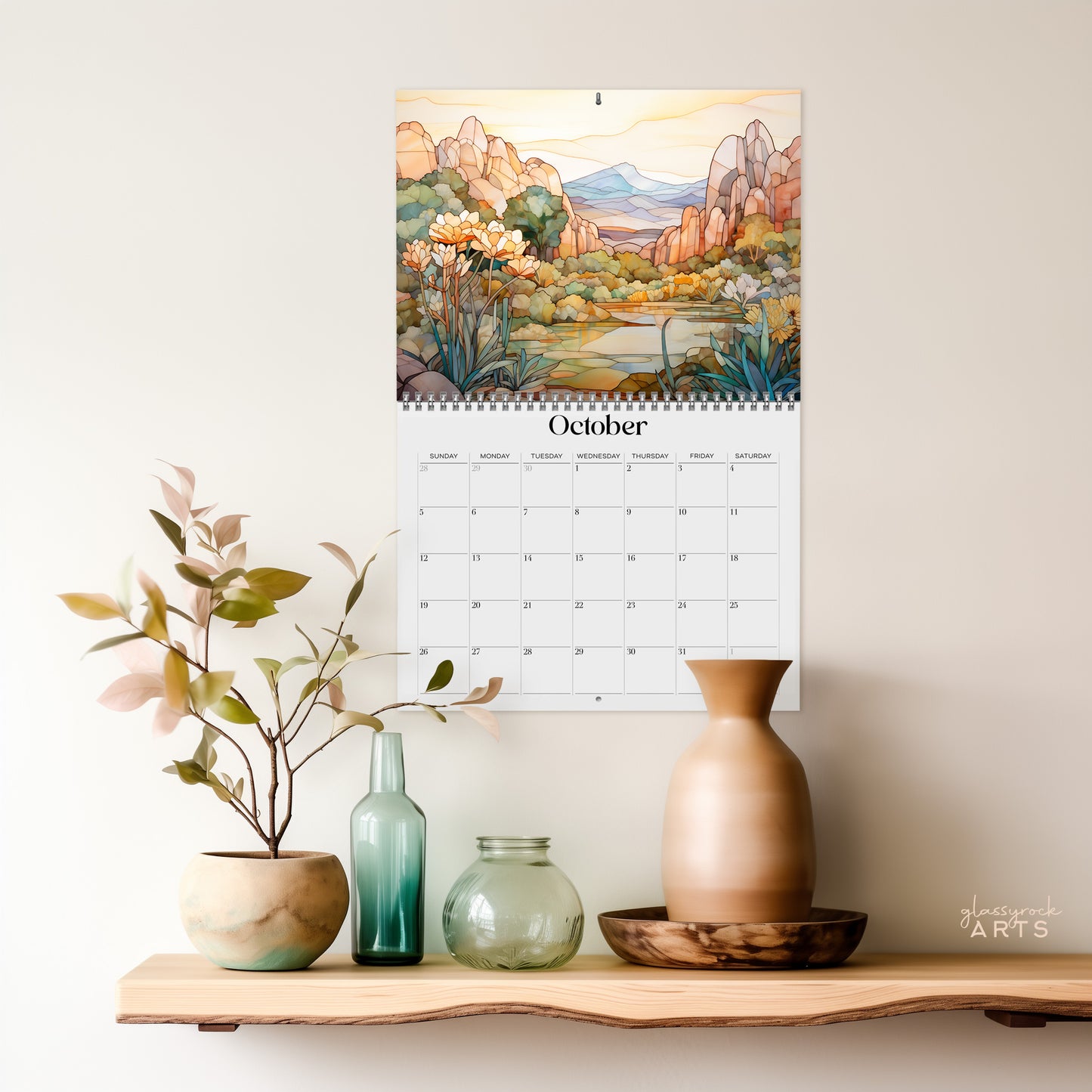 The 2025 Wall Calendar - Stained Glass Desert Landscapes, with spiral binding and a centered hole for hanging, features vivid desert illustrations. 