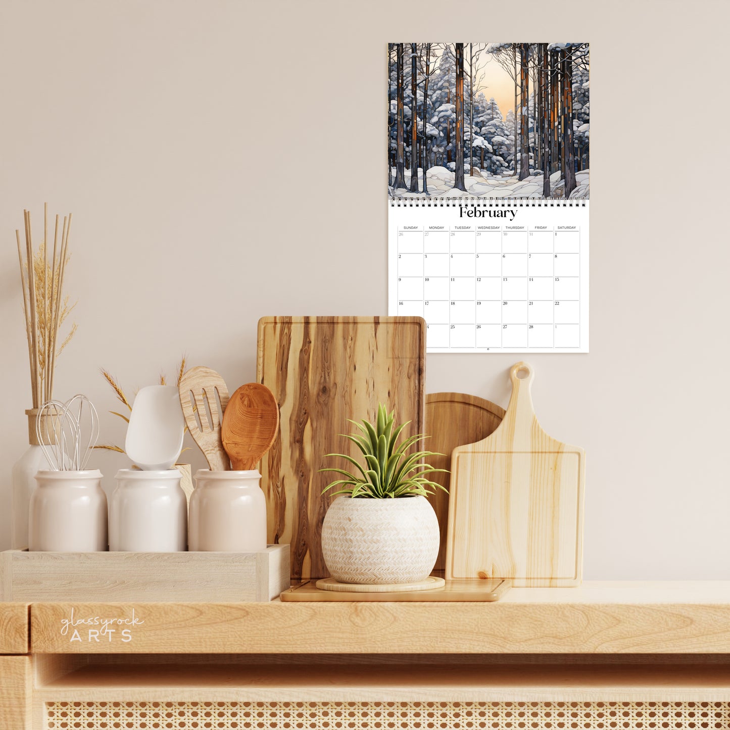 The forests calendar hanging in a kitchen with kitchen tools below on a counter.