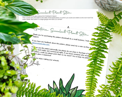 A printed letter titled Gasteria Succulent Plant Stem rests on a white surface with digital patterns of green plants. Fern leaves frame the right, while a small stack of the Stained Glass Succulent Stems Pattern Pack of 4 peeks from the top left, adorned with stained glass plant designs.