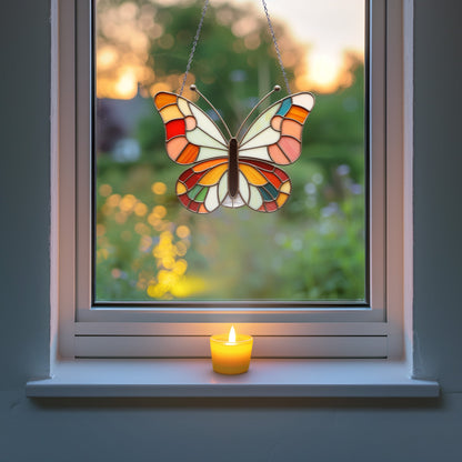 A stained glass butterfly hangs in a window with a garden view, a lit candle rests on the sill, and the background shows an evening scene with a soft sunset.