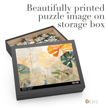 Open the Stained Glass Monstera Leaves Jigsaw Puzzle box to reveal pieces inside and a lid with botanical art reminiscent of stained glass, featuring large orange, green, and beige leaves. The text reads: Beautifully printed puzzle image on storage box. Ideal as an art or couples gift.