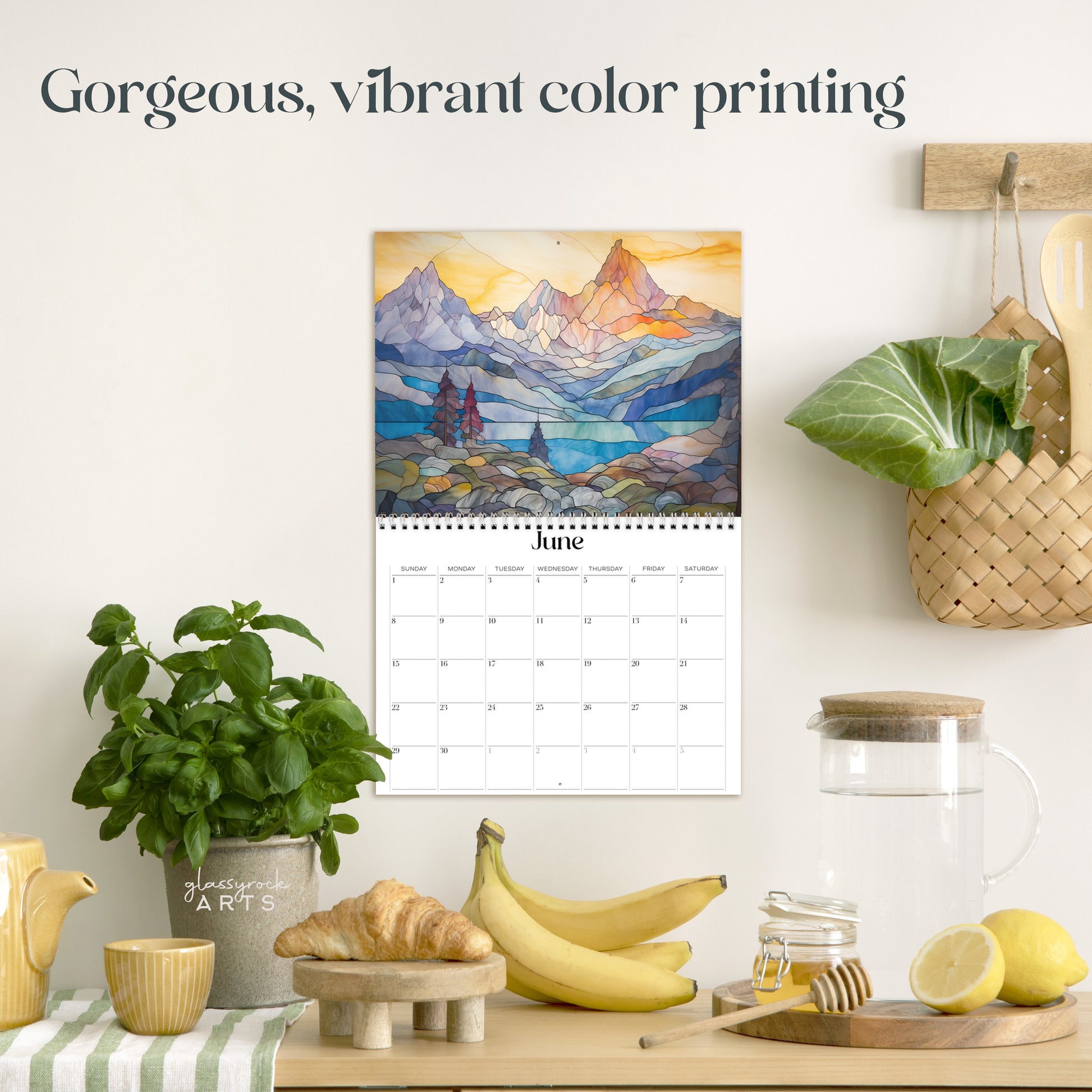 The moutains calendar hanging in a kitchen with kitchen tools below on a counter. It has gorgeous, vibrant color printing on premium paper.