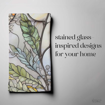 A folded fabric with a stained glass-inspired leaf and floral design on a gray background. Text: "Stained Glass Nouveau Ferns for your home" in large, decorative font. This stunning Stained Glass Nouveau Ferns Dish Towel is the perfect custom creation to add an artistic touch to your space.