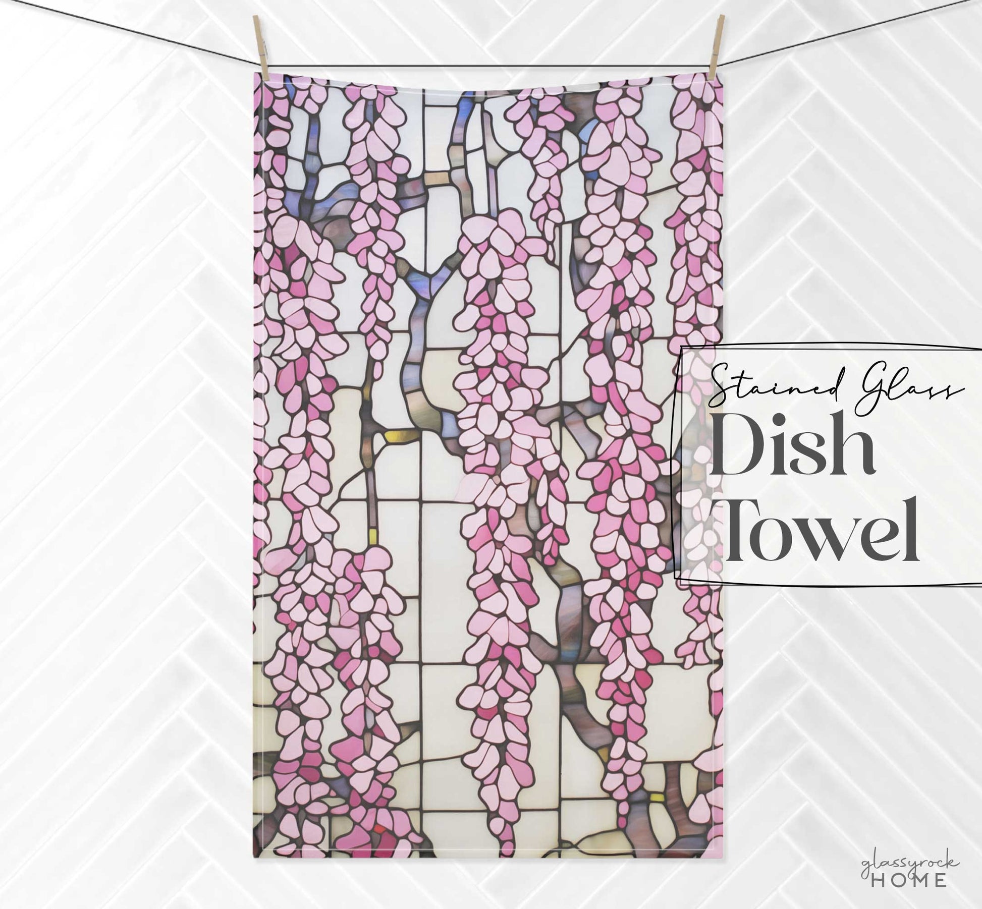 The Stained Glass Pink Wisteria Dish Towel showcases a unique design that resembles stained glass, with cascading flowers set against a white patterned background. The name "Stained Glass Dish Towel" is printed on the right side.