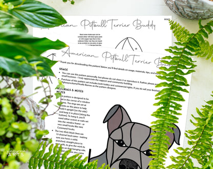 The American Pitbull Terrier Dog Stained Glass Pattern features a printed quilt block design with an abstract pitbull face in the bottom right, surrounded by green fern leaves. The paper includes details on usage, materials, and notes.