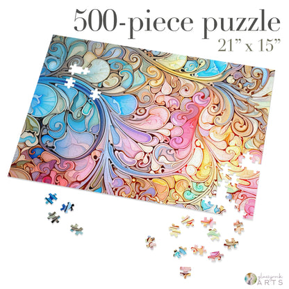 Partially assembled, the Stained Glass Rainbow Paisley Jigsaw Puzzle is a vivid 500-piece set with swirling blue, pink, and gold patterns. Some pieces lie scattered on a white surface. Measuring 21 x 15, this puzzle by a renowned stained glass artist is an ideal gift for enthusiasts.