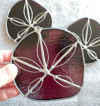 Three purple handmade stained glass sand dollars with handworked wire accents 