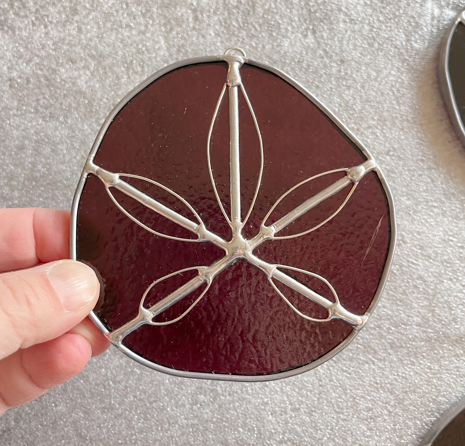 A purple handmade stained glass sand dollar with handworked wire accents, christmas tree ornaments, suncatchers