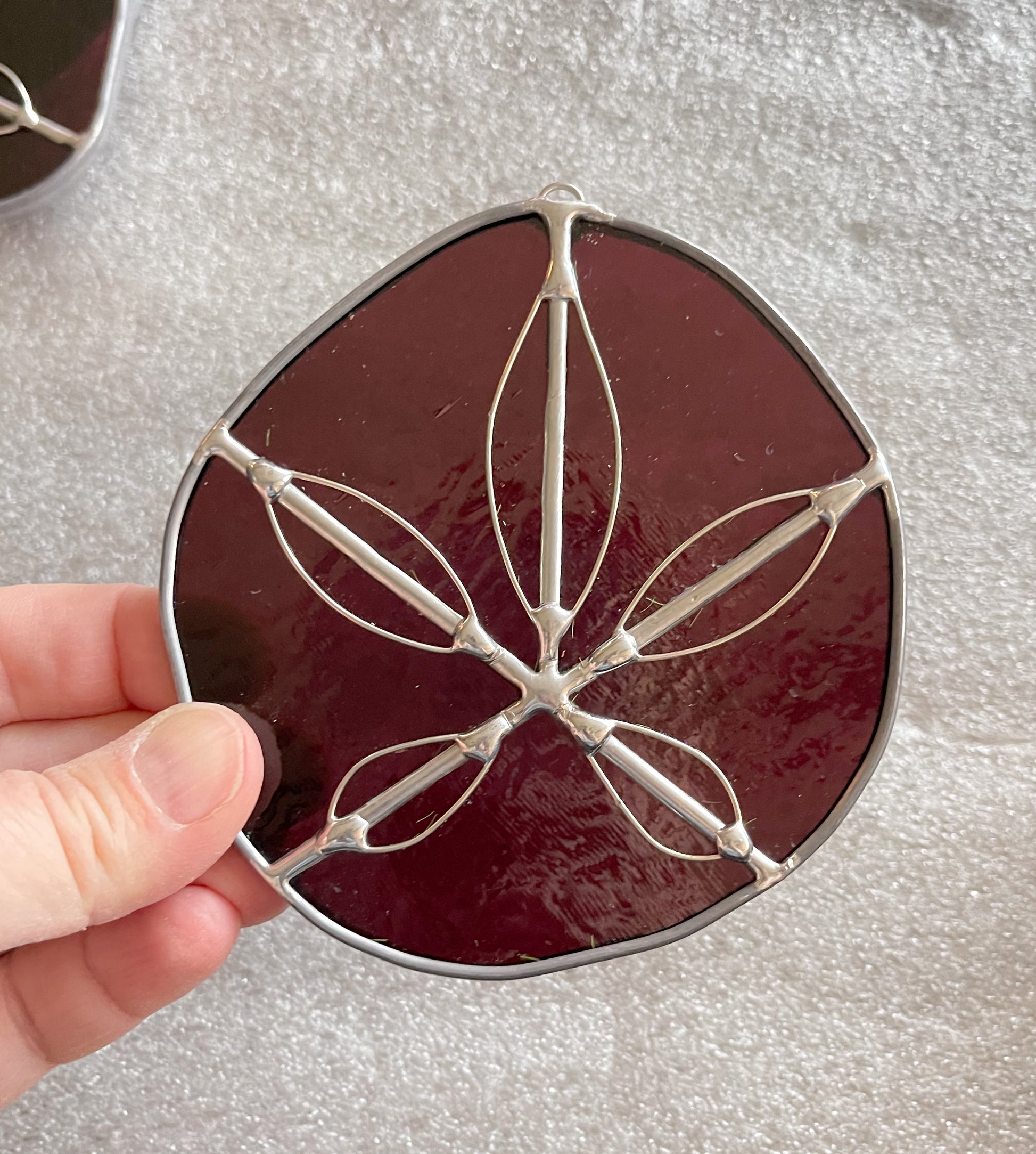 A purple handmade stained glass sand dollar with handworked wire accents, christmas tree ornaments, suncatchers