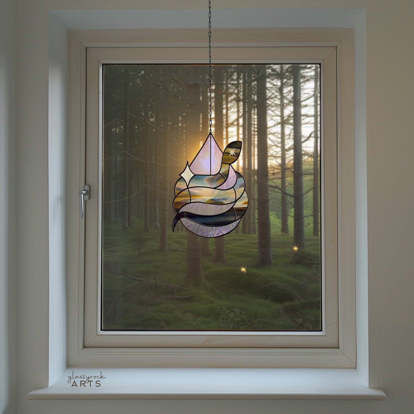 A Snake Stained Glass Pattern Rain Drop ornament hangs in the window, framing the forest view. Sunlight filters through the trees, casting a warm and serene light that dances across the room.