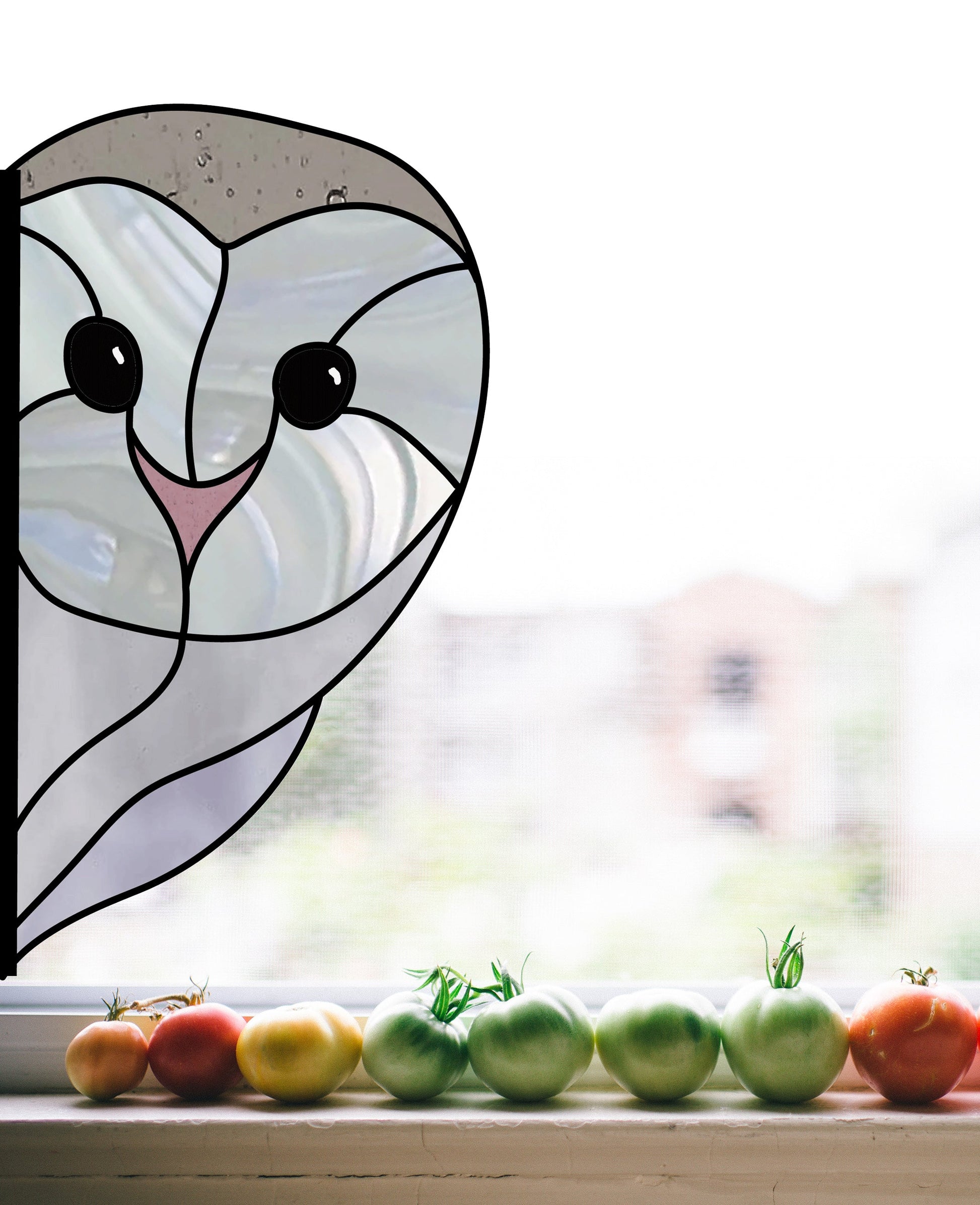 A captivating Snowy Owl Stained Glass design adorns the window, casting colorful reflections. Ripening tomatoes line the windowsill below, while a blurred cityscape serves as a backdrop for this enchanting digital pattern download available with a commercial license.