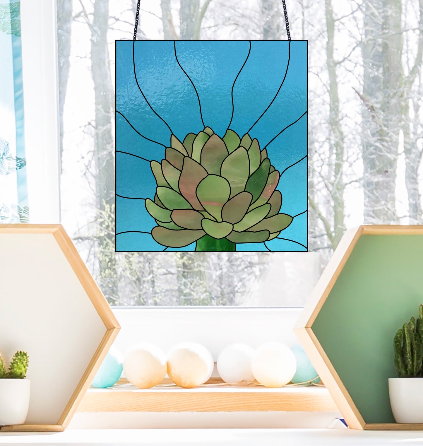 The Three Succulent Stained Glass Panel Patterns offer a green plant on a blue background design, perfect for windows with snowy views and bare trees. Displayed alongside are wooden hexagon shelves with small plants and spheres, ideal for fans of digital patterns or those needing a commercial license.