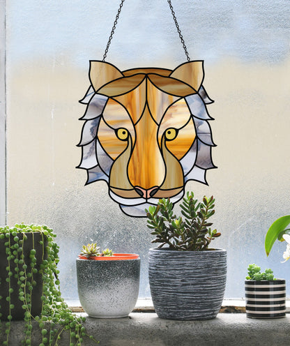 The Tiger Eyes Stained Glass Pattern hangs against a frosted window, complemented by three plant pots below: one with cascading succulents, another with mixed small plants, and the third adorned with a digital design featuring a solitary orchid bloom.