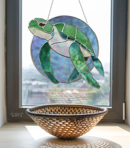 A stunning Round Stained Glass Turtle Pattern sun catcher hangs in the window, casting vibrant reflections, while a woven basket rests on the windowsill.