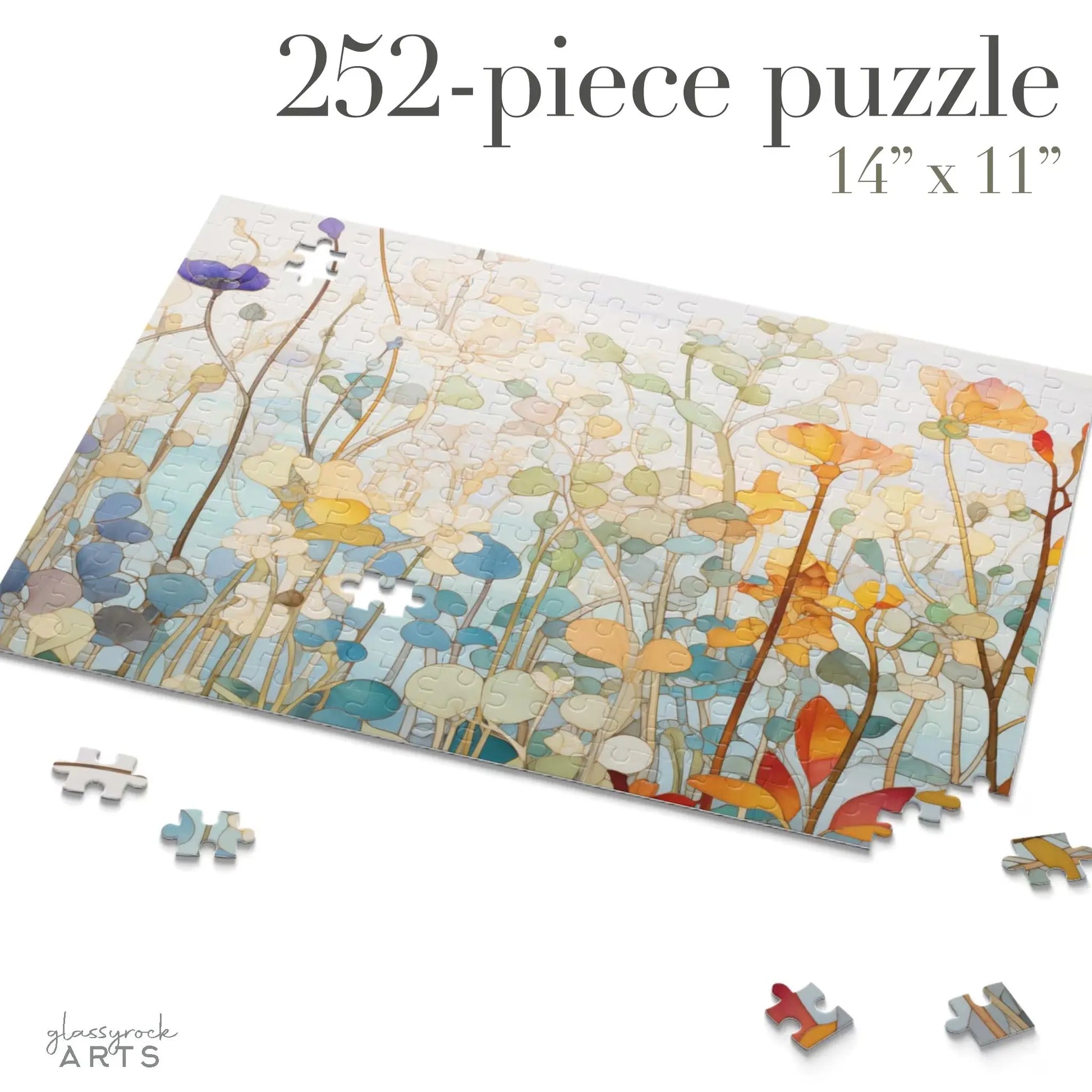 The Wildflower Botanicals Jigsaw Puzzle is a partially completed 252-piece set highlighting a colorful illustration of tall, abstract plants with rounded tops. Loose pieces surround the art, featuring a stained glass-inspired design, with dimensions of 14 x 11 displayed above.