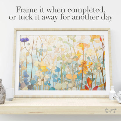 The Wildflower Botanicals Jigsaw Puzzle features vibrant abstract flowers and leaves in blue, orange, yellow, and green. Its stained glass-inspired design is perfect for framing on a shelf or saving for later.