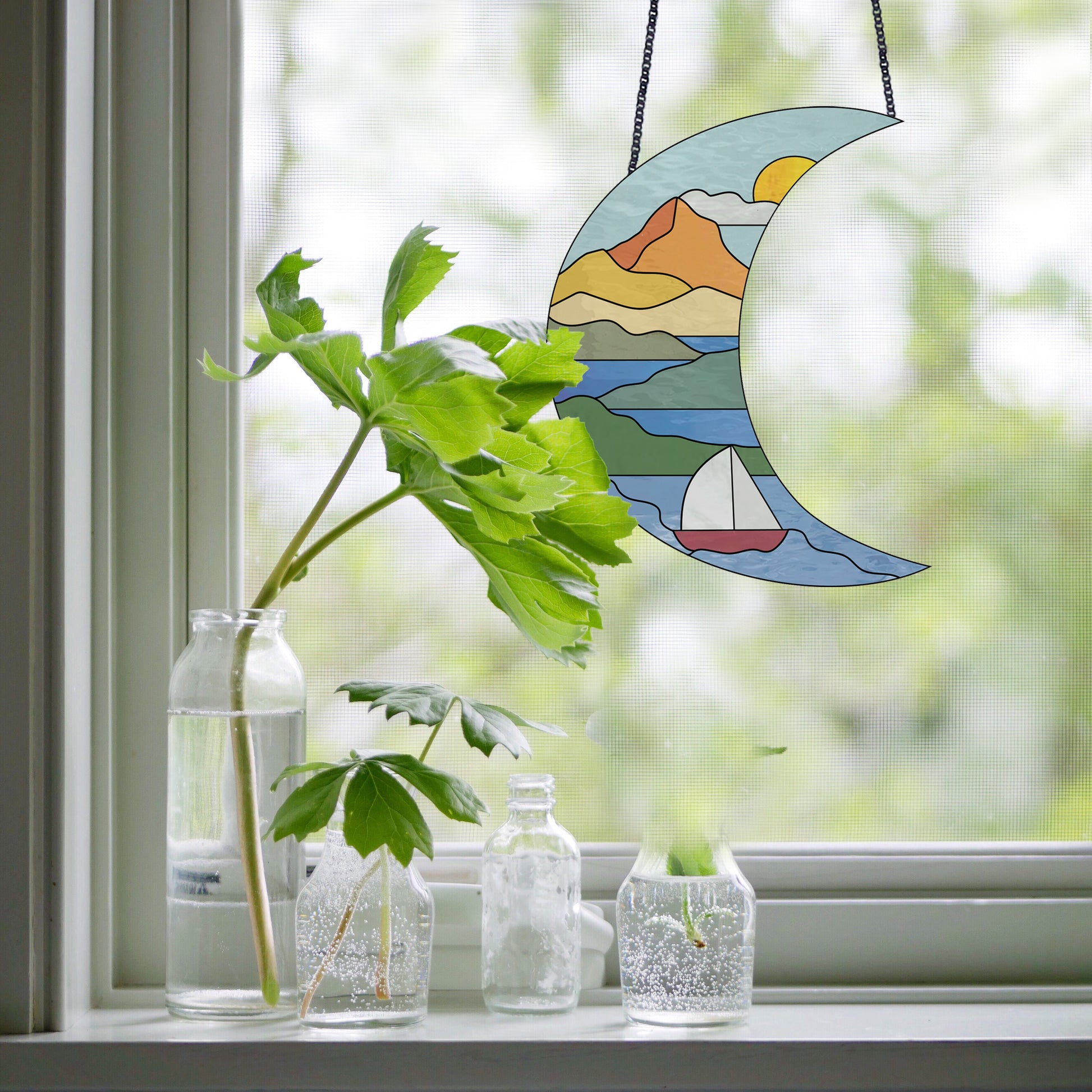 Stained glass pattern for a boho seascape crescent moon, instant PDF download, shown in a window with plants