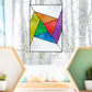 Beginner stained glass pattern of an abstract rainbow pinwheel, instant PDF download, shown hanging in a wintry window